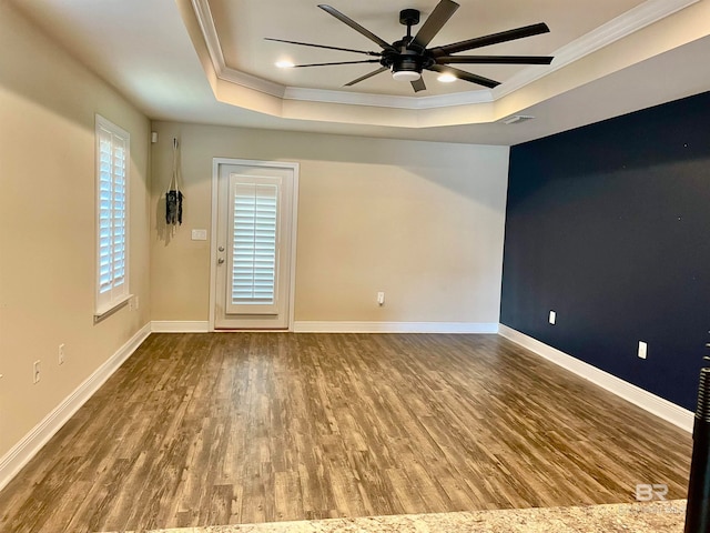 empty room featuring hardwood / wood-style flooring, ceiling fan, crown molding, and a tray ceiling