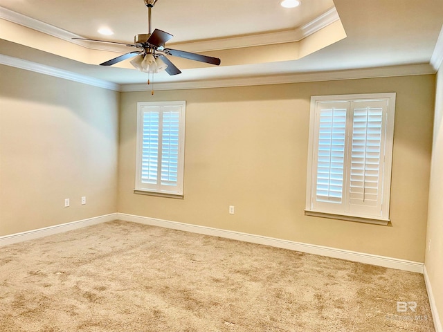 empty room with ceiling fan, a raised ceiling, and ornamental molding