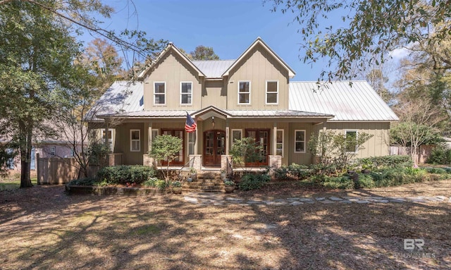 view of front facade with a porch, metal roof, board and batten siding, and fence