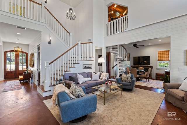 living area featuring visible vents, concrete flooring, a towering ceiling, and stairs