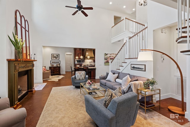 living room with a ceiling fan, baseboards, recessed lighting, a fireplace, and stairs