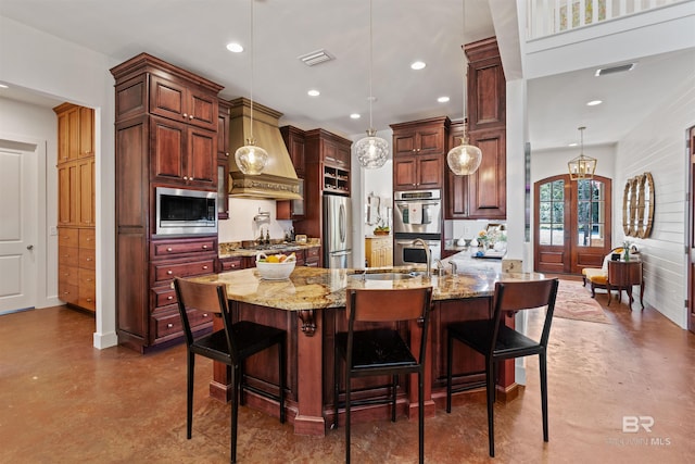 kitchen featuring light stone counters, stainless steel appliances, custom exhaust hood, and visible vents