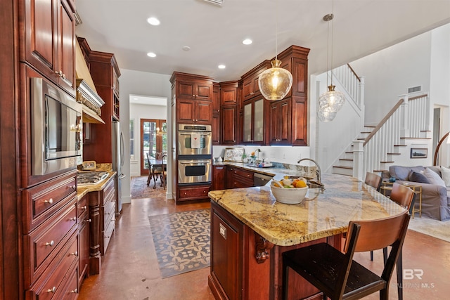 kitchen featuring light stone counters, a breakfast bar, a peninsula, stainless steel appliances, and pendant lighting