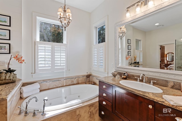 full bath featuring visible vents, a jetted tub, vanity, and an inviting chandelier