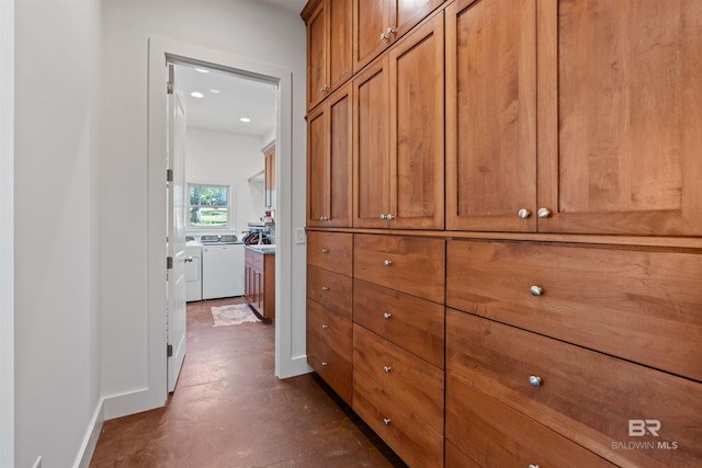 hallway featuring concrete floors, baseboards, and separate washer and dryer