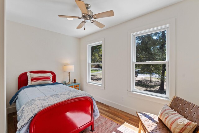 bedroom with a ceiling fan, wood finished floors, and baseboards