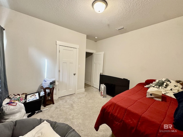carpeted bedroom with a textured ceiling and visible vents