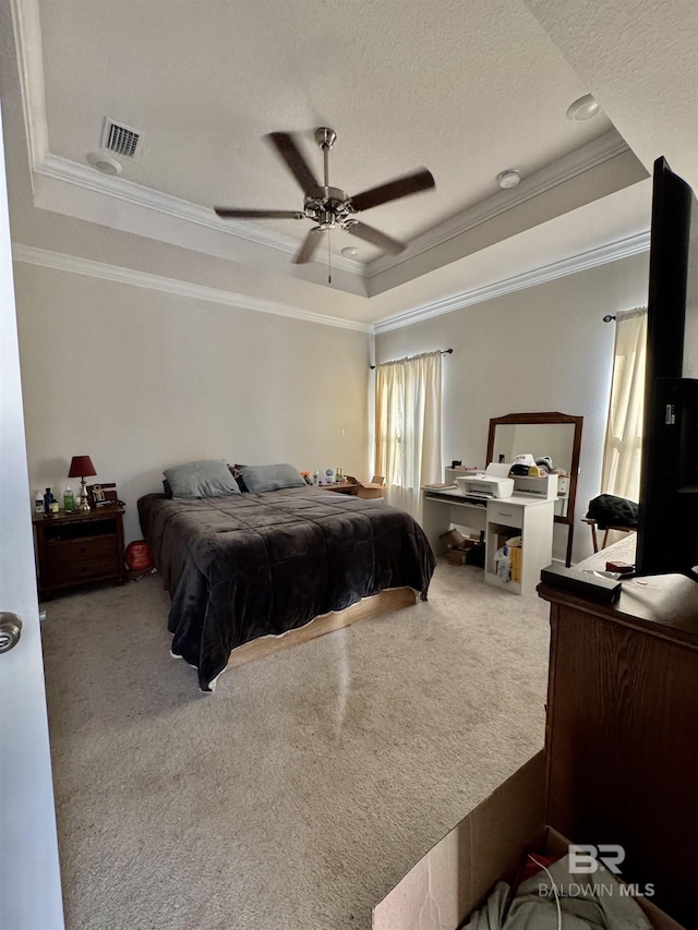 bedroom with ornamental molding, a tray ceiling, carpet flooring, and visible vents