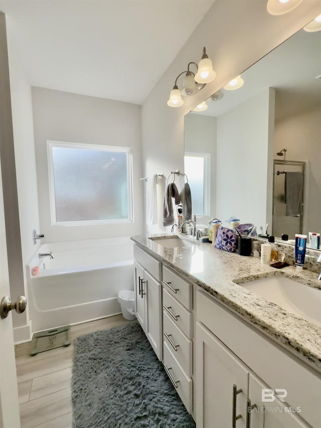 bathroom with double vanity, walk in shower, a sink, and a bath
