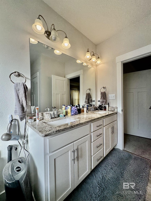 bathroom with a sink, a textured ceiling, and double vanity