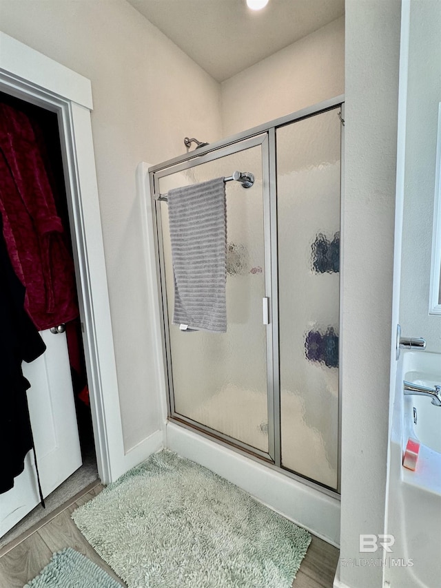 bathroom with a stall shower and wood finished floors