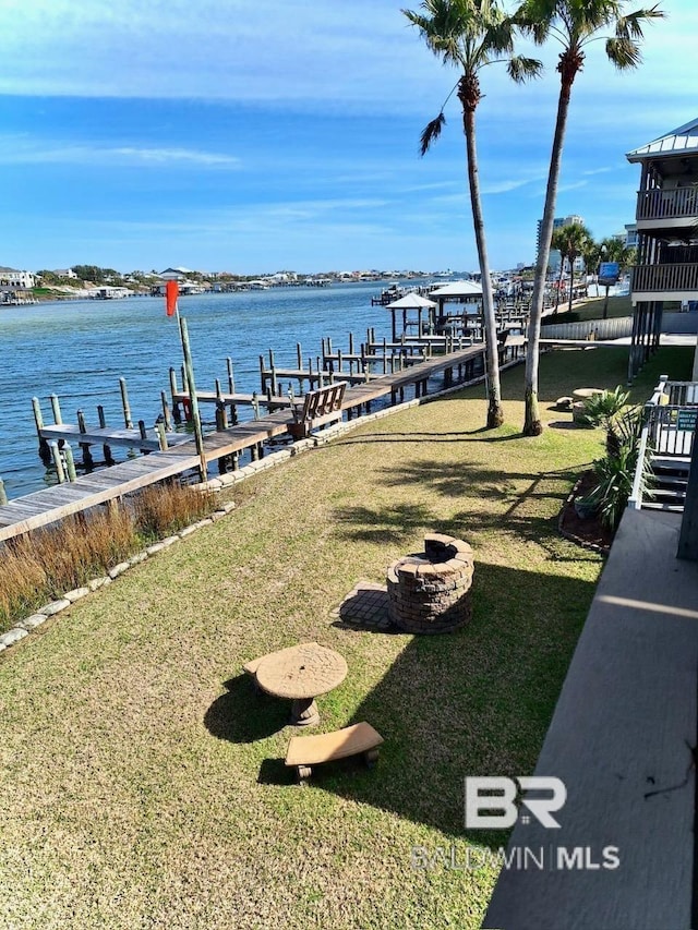 dock area with a water view, a lawn, and a fire pit