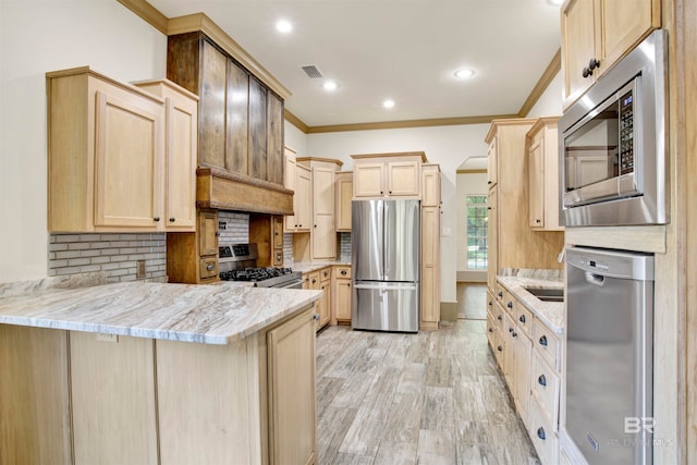 kitchen featuring light brown cabinetry, decorative backsplash, appliances with stainless steel finishes, and light hardwood / wood-style floors