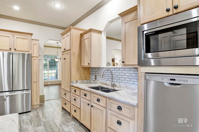 kitchen featuring light brown cabinetry, stainless steel appliances, light wood-type flooring, ornamental molding, and backsplash