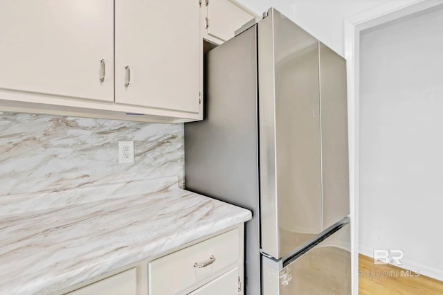 18 Rollins Pl, Atmore, AL 36502 - kitchen featuring freestanding refrigerator, backsplash, light wood-type flooring, white cabinetry, and light stone countertops