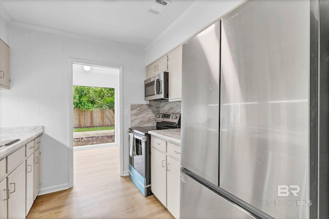 18 Rollins Pl, Atmore, AL 36502 - kitchen with appliances with stainless steel finishes, crown molding, light wood-style floors, light countertops, and white cabinetry
