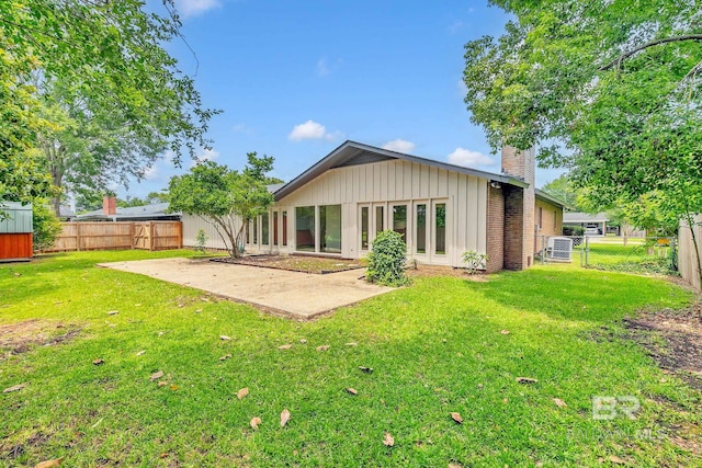18 Rollins Pl, Atmore, AL 36502 - rear view of house with a chimney, a patio, board and batten siding, and a fenced backyard