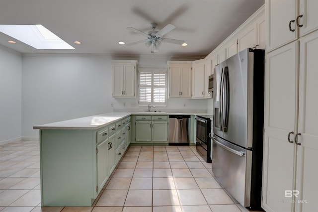 kitchen featuring green cabinetry, sink, a skylight, light tile patterned floors, and appliances with stainless steel finishes