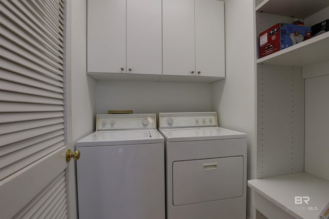 clothes washing area with cabinets and washing machine and clothes dryer