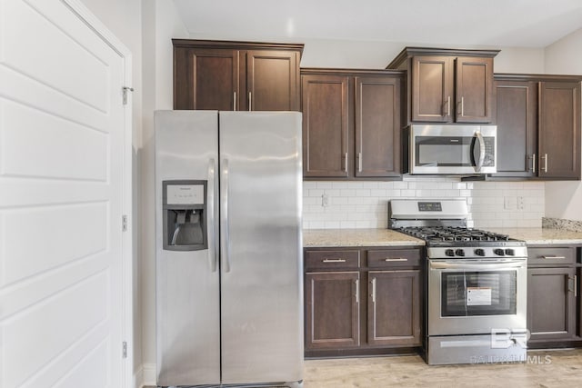 31689 Kestrel Loop, Spanish Fort, AL 36527 - kitchen with appliances with stainless steel finishes, light stone counters, decorative backsplash, and dark brown cabinets