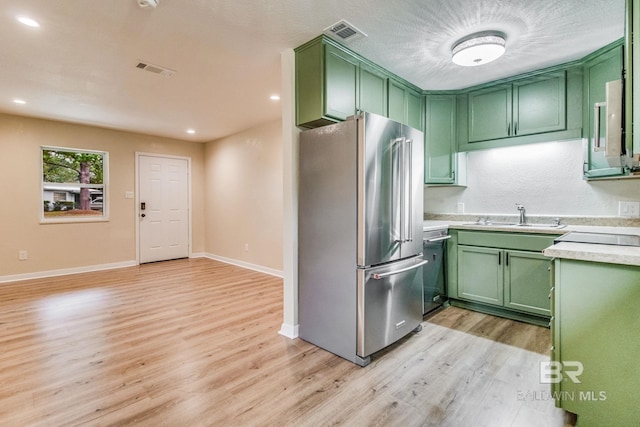 kitchen with green cabinetry, stainless steel appliances, light hardwood / wood-style floors, and sink