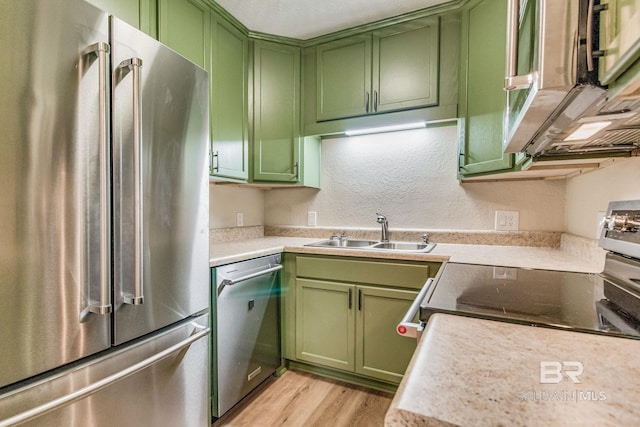 kitchen featuring stainless steel appliances, sink, light hardwood / wood-style floors, and green cabinetry