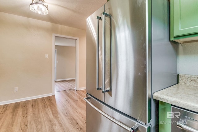 kitchen featuring high quality fridge, light hardwood / wood-style floors, a textured ceiling, and green cabinetry