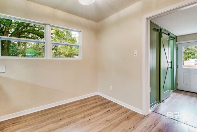 unfurnished room featuring a barn door and light wood-type flooring