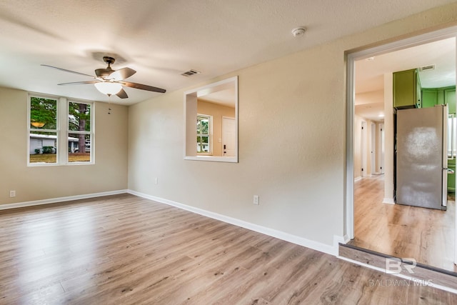 empty room featuring ceiling fan, light hardwood / wood-style flooring, and a textured ceiling