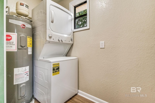 laundry room featuring stacked washer / drying machine, hardwood / wood-style flooring, and water heater