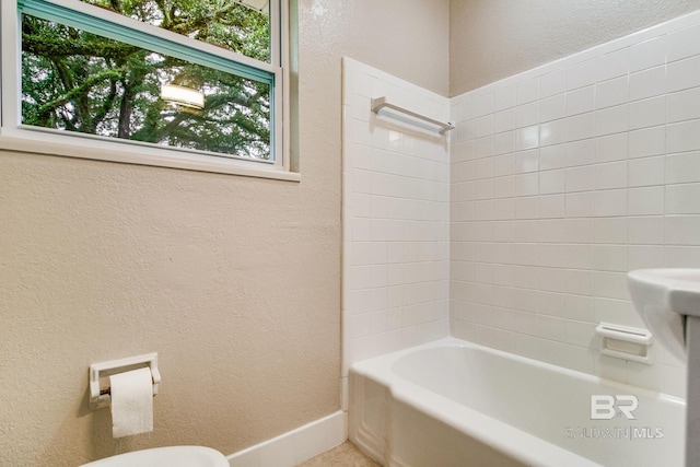 bathroom featuring tiled shower / bath combo and toilet