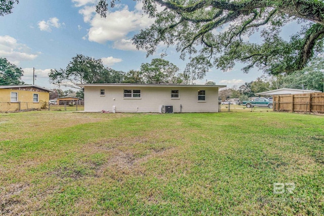 rear view of property featuring a yard and cooling unit