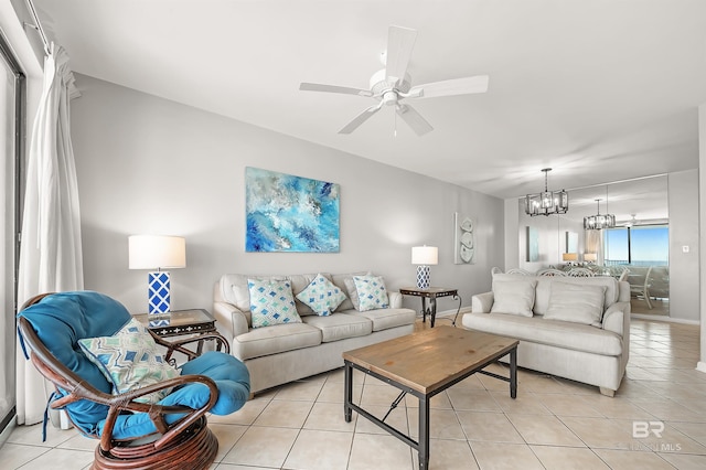 living area with baseboards, ceiling fan with notable chandelier, and light tile patterned flooring