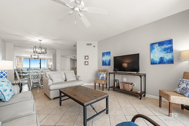 living area featuring ceiling fan with notable chandelier, light tile patterned flooring, visible vents, and baseboards