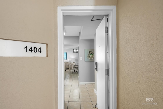 hallway featuring light tile patterned floors and a textured wall