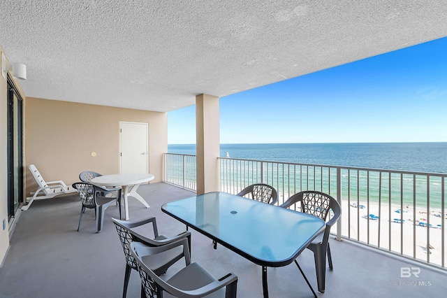 balcony featuring a water view, outdoor dining area, and a view of the beach