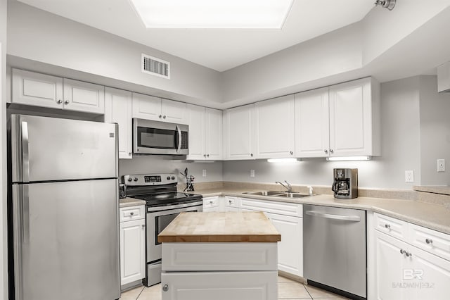 kitchen featuring a center island, stainless steel appliances, butcher block counters, visible vents, and a sink