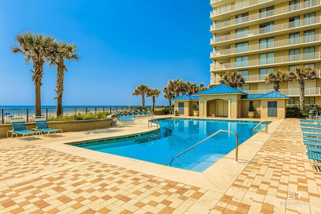 community pool featuring a water view, fence, and a patio