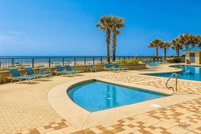 community pool featuring a water view, fence, and a patio