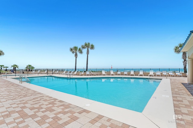 community pool with a patio area and fence