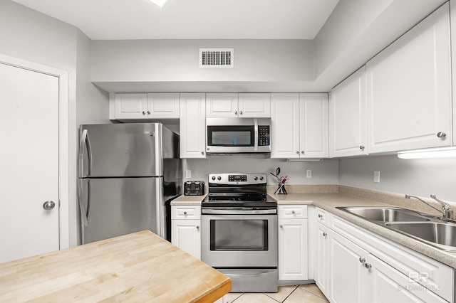 kitchen with stainless steel appliances, visible vents, a sink, and white cabinetry