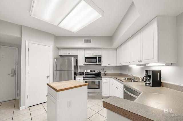 kitchen featuring light tile patterned floors, stainless steel appliances, butcher block counters, visible vents, and a sink