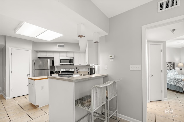 kitchen featuring appliances with stainless steel finishes, visible vents, a peninsula, and light tile patterned floors