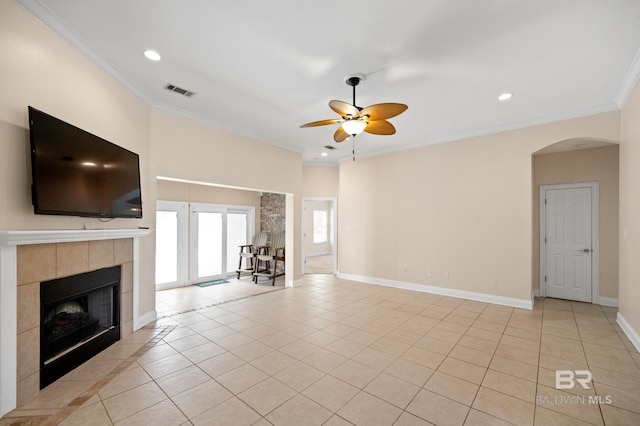 unfurnished living room featuring crown molding, a tiled fireplace, light tile patterned floors, and ceiling fan