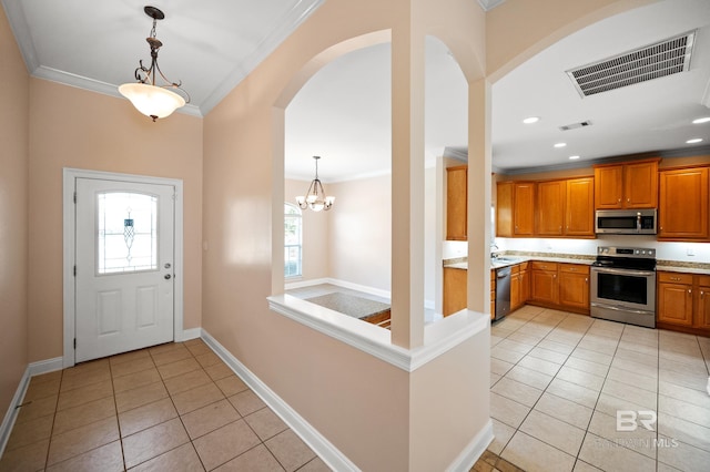 foyer with ornamental molding, a chandelier, and light tile patterned floors