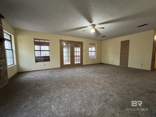 carpeted spare room featuring plenty of natural light, a textured ceiling, and french doors