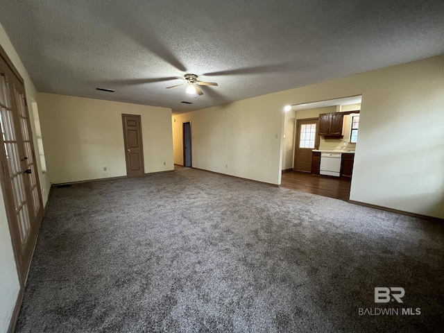 unfurnished living room featuring ceiling fan, a textured ceiling, and dark colored carpet