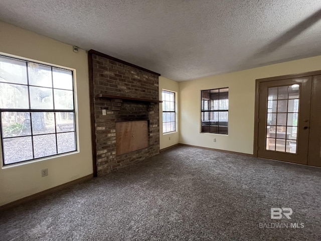 unfurnished living room with a fireplace, a textured ceiling, and dark colored carpet