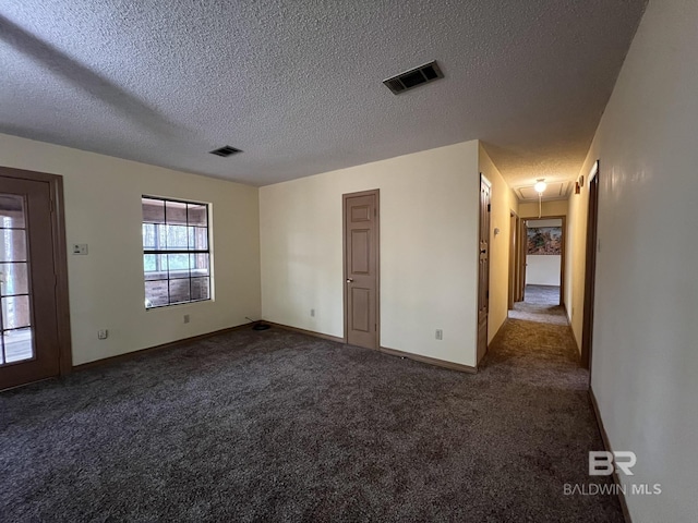 empty room with a textured ceiling and dark colored carpet