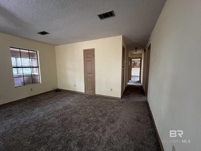 carpeted spare room with a textured ceiling